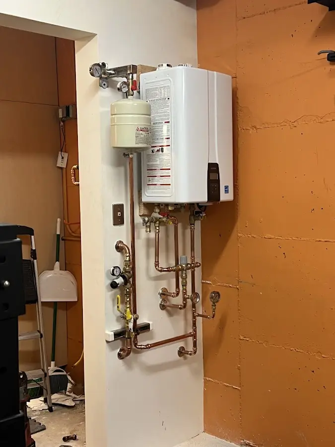 Plumbing technician inspecting water heater connections in Ralston
